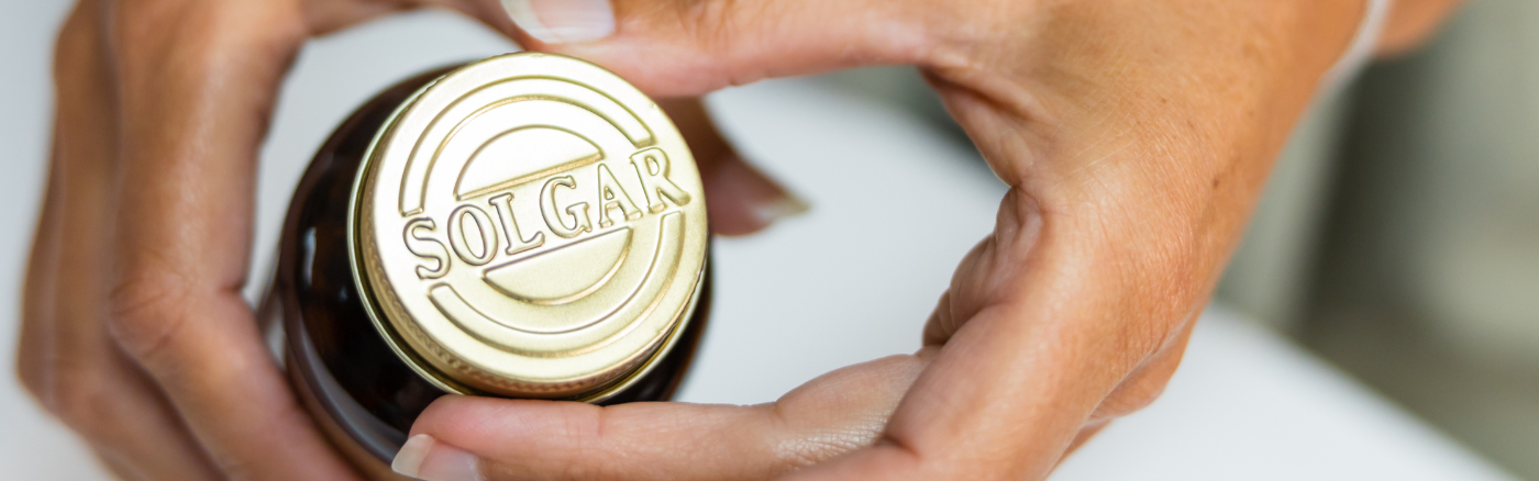 A person holding a Solgar capsule featuring the brand logo.
