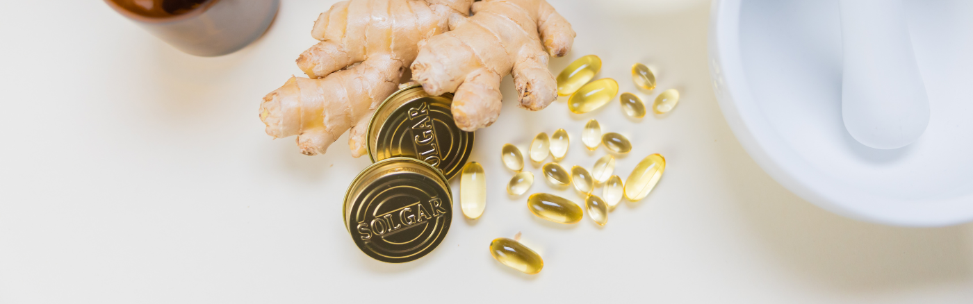Pills, a ginger root and 2 capsule lids featuring the Solgar brand - The Gold Standard in Vitamins.