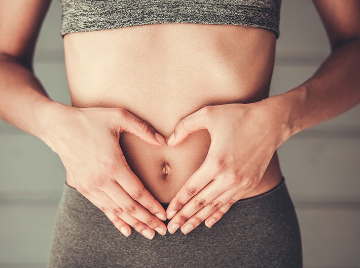 Digestive health with a woman forming a heart with her hands on her belly.