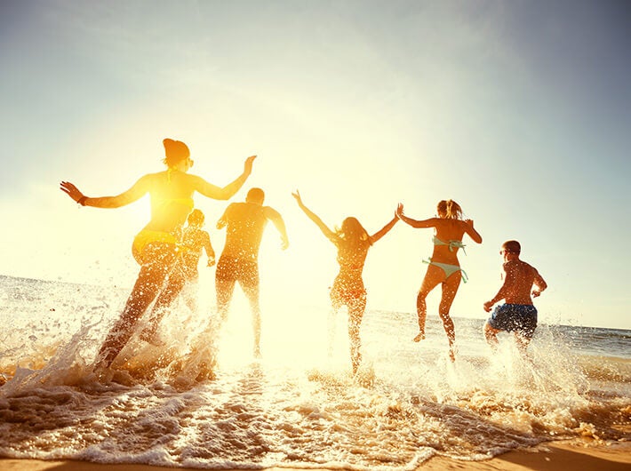 A group of energetic people entering the sea water.